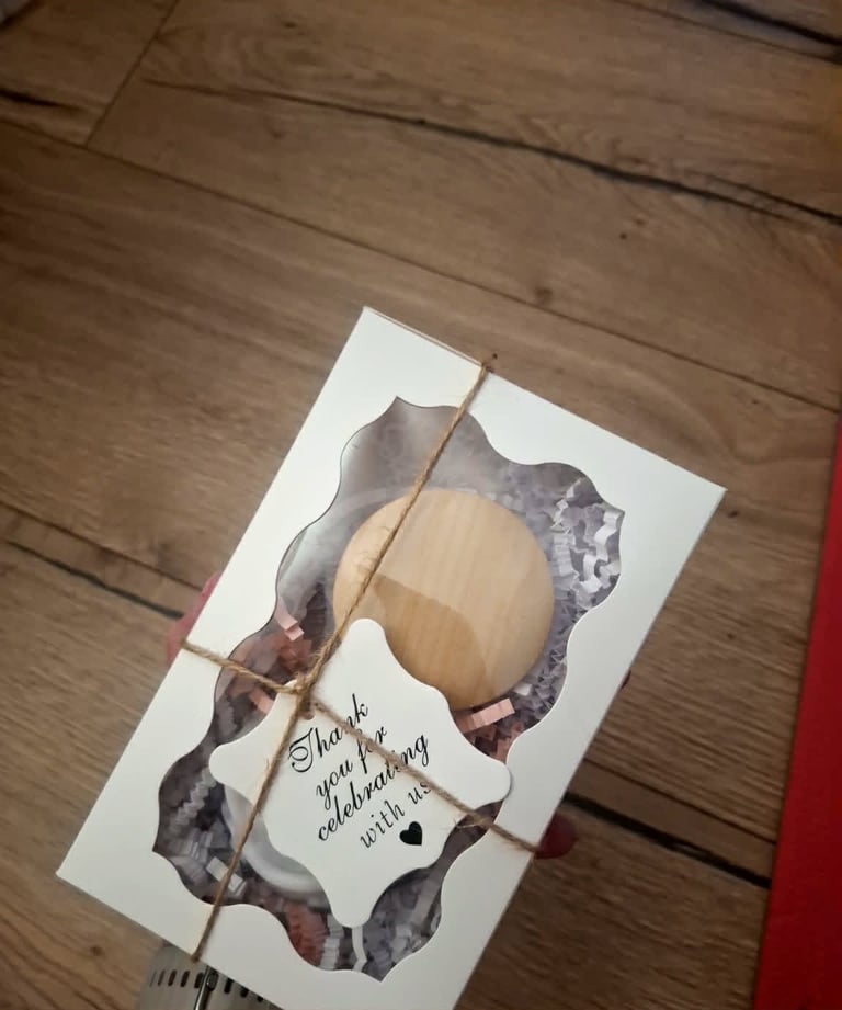 Handmade thank you card with pressed flowers, wooden circle charm, twine, and handwritten message on wooden surface